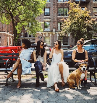 four women sitting on black steel bench during daytime