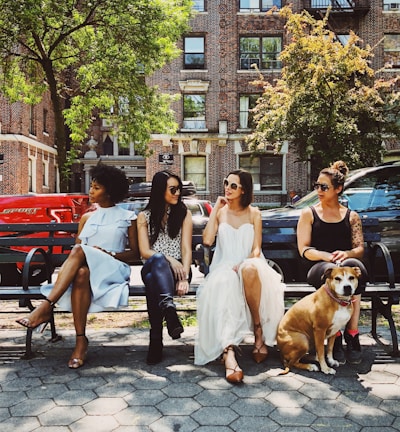 four women sitting on black steel bench during daytime