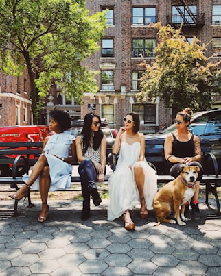 four women sitting on black steel bench during daytime