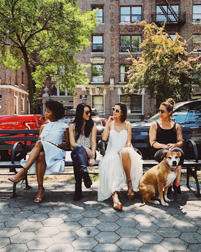 four women sitting on black steel bench during daytime