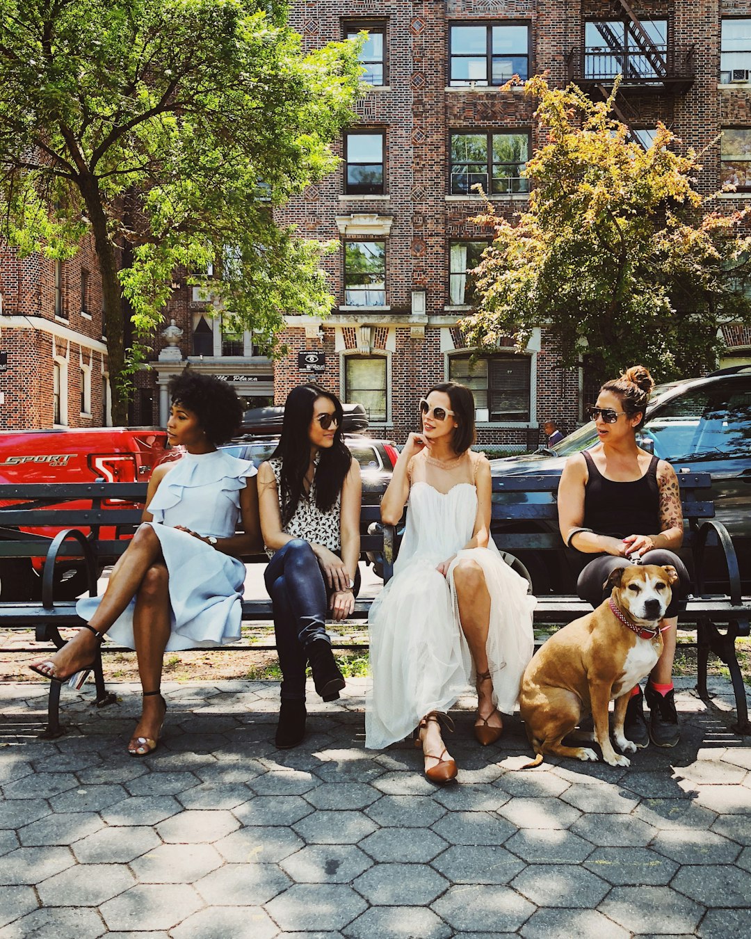 four women sitting on black steel bench during daytime