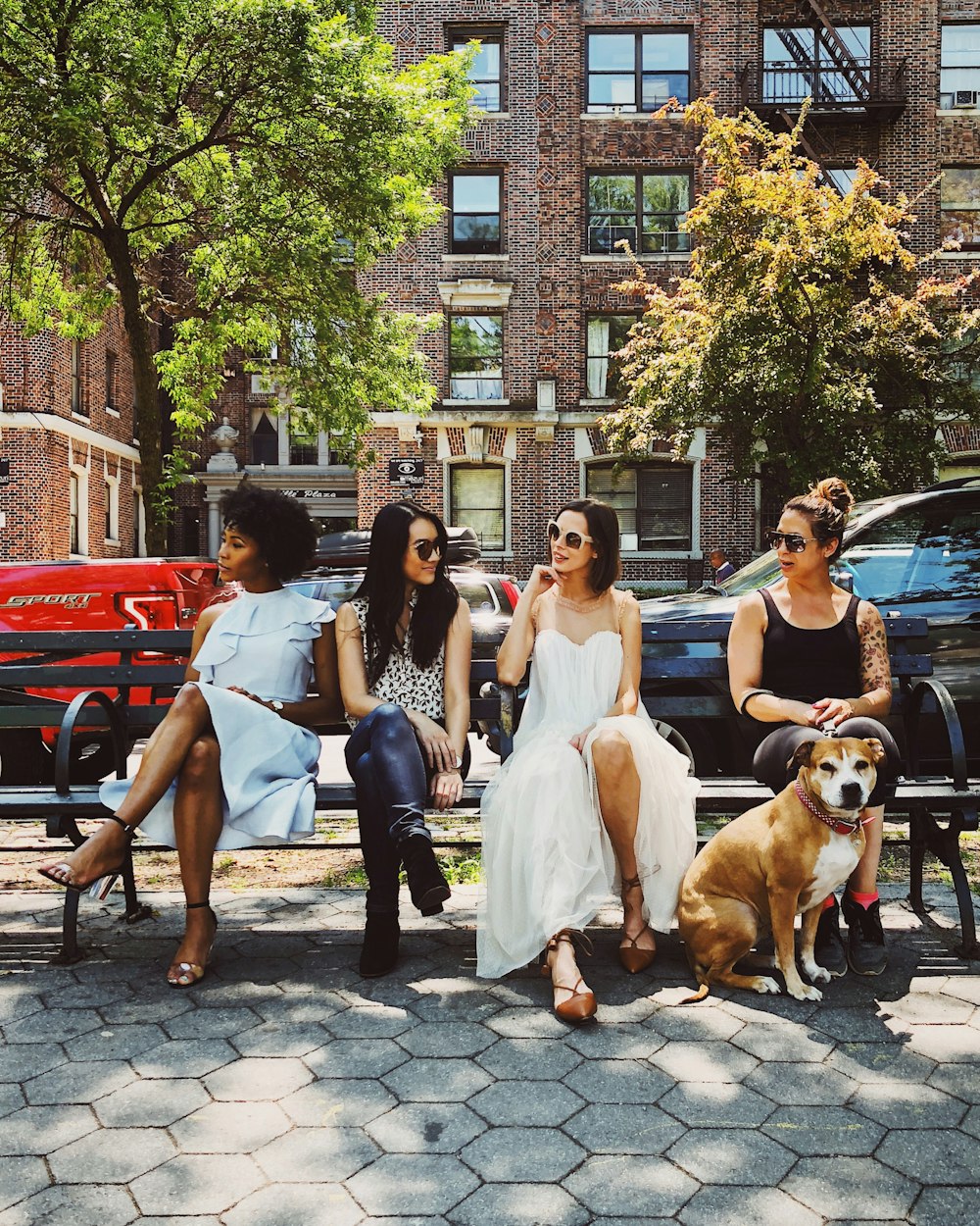 four women sitting on black steel bench during daytime