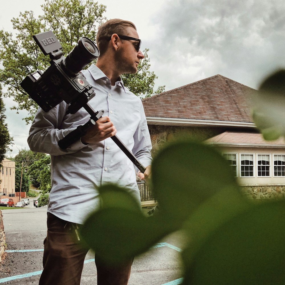 man in gray dress shirt holding camera