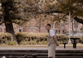 man standing on big chessboard with chest pieces at park