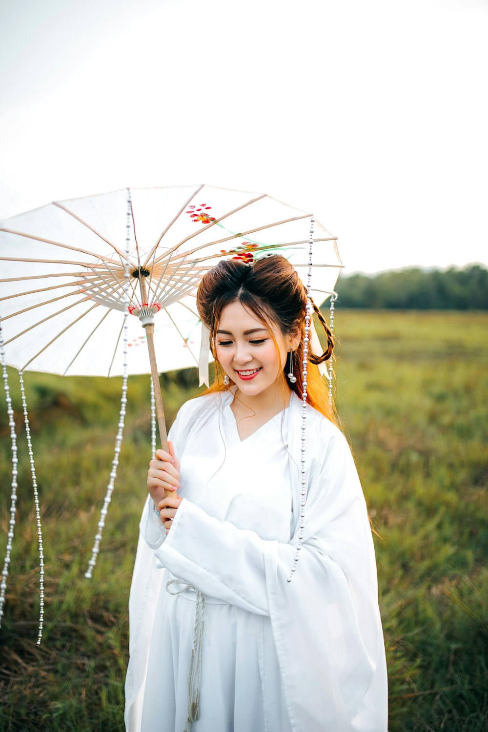 mujer con vestido de kimono blanco y sosteniendo paraguas blanco