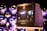 A vintage Sony Trinitron television is placed on a stand, displaying a blurred scene of lights and figures, possibly from a cityscape. The background features multiple reflective spheres, creating an artistic and modern ambiance.