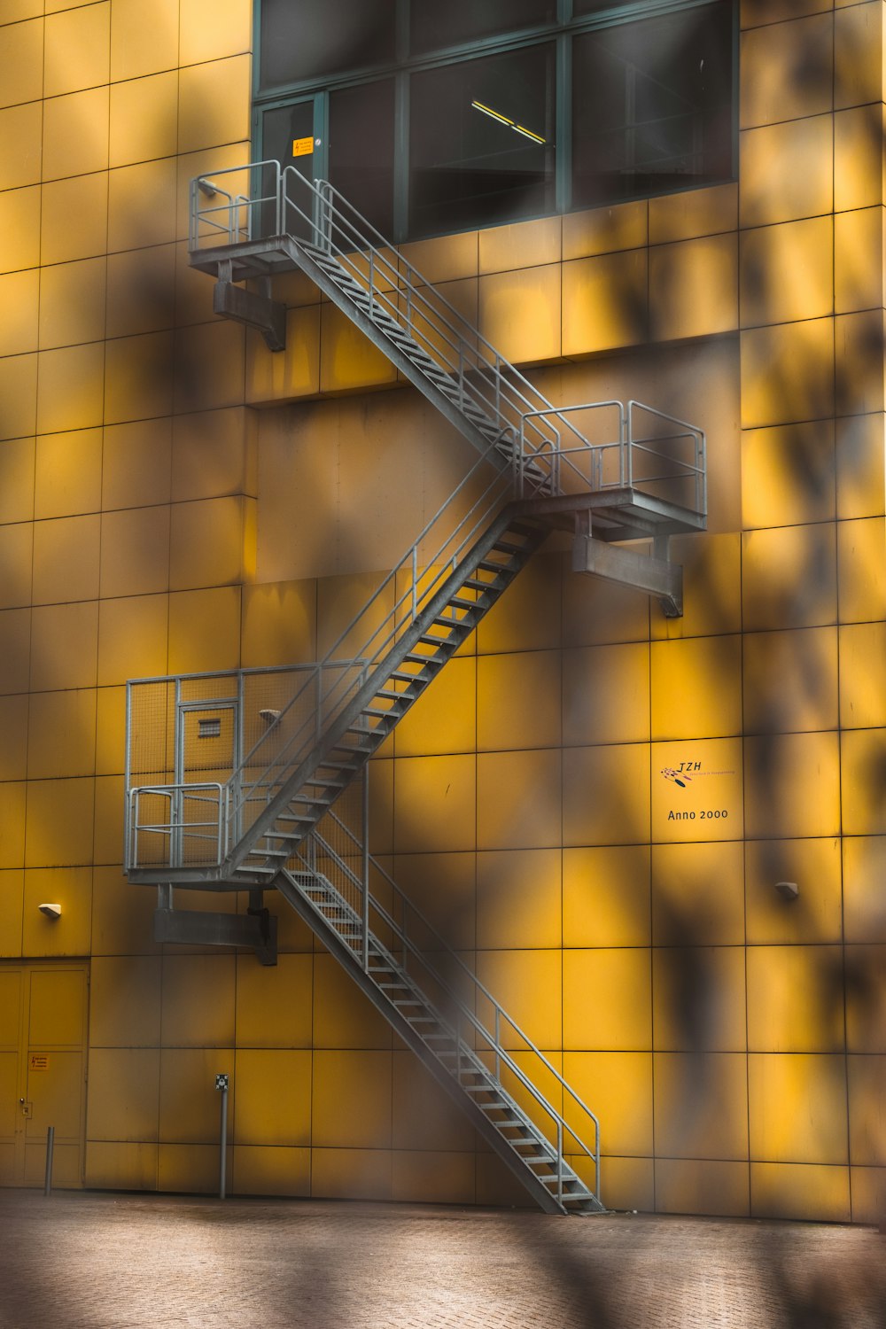 黄色い建物の横の灰色の鋼のはしご