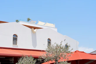A wide shot of a commercial building with multiple muted blue awnings providing shade on a sunny day.
