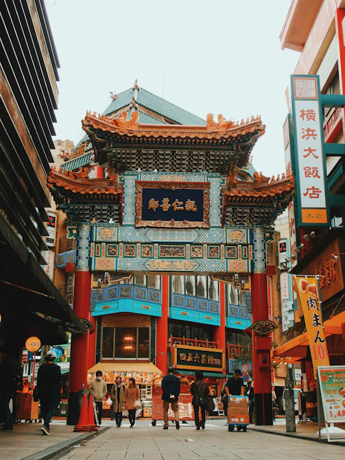 A traditional Chinese gate in Yokohama Chinatown with people walking on the street