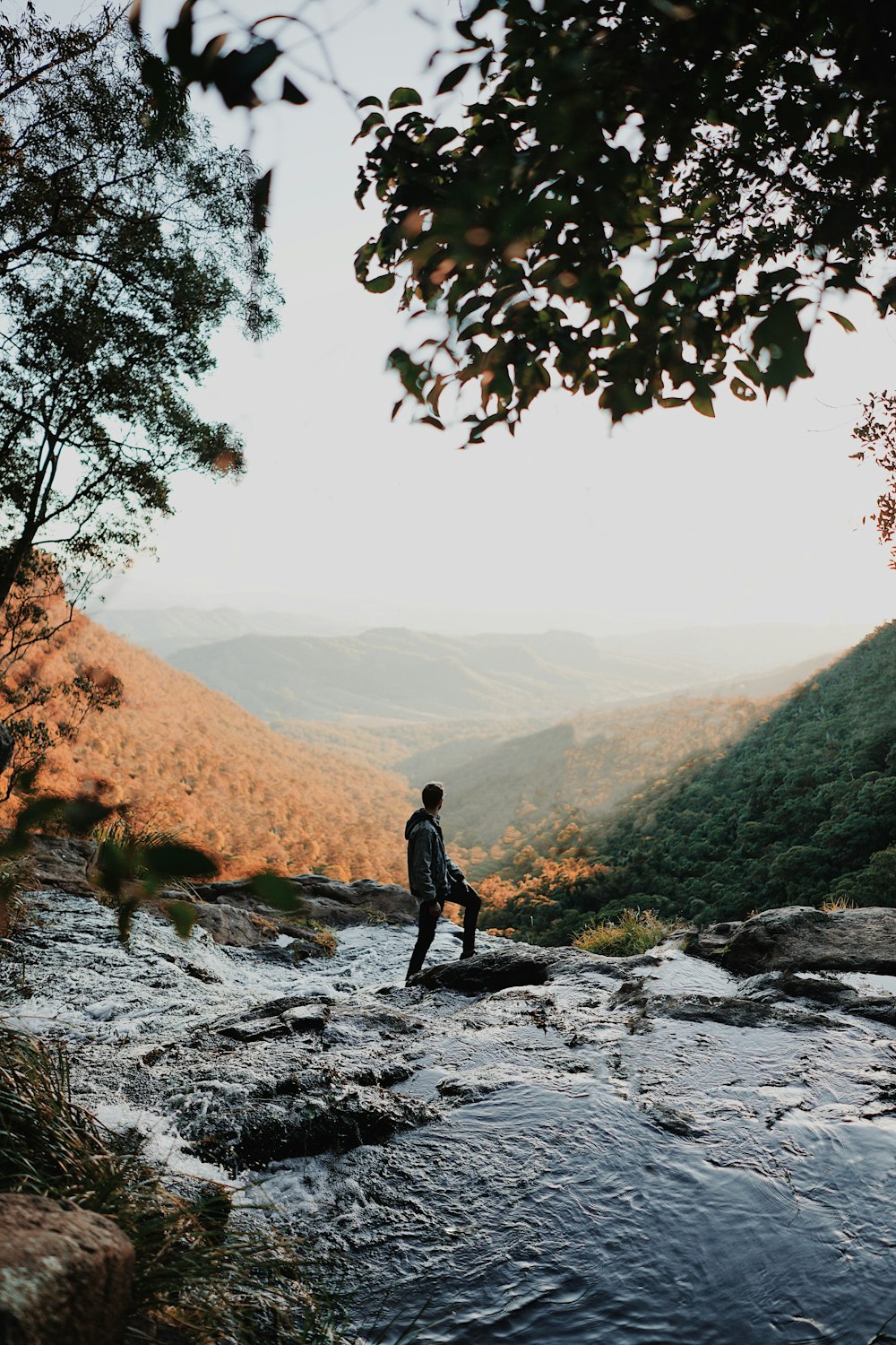 man standing on lake surrounded by trees