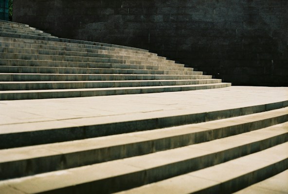 Broad stone steps rising in warm light against a dark wall