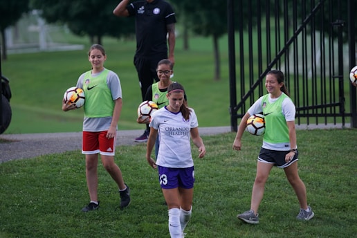 A professional coach guiding a joyful group of bubble football players wearing bright gear.