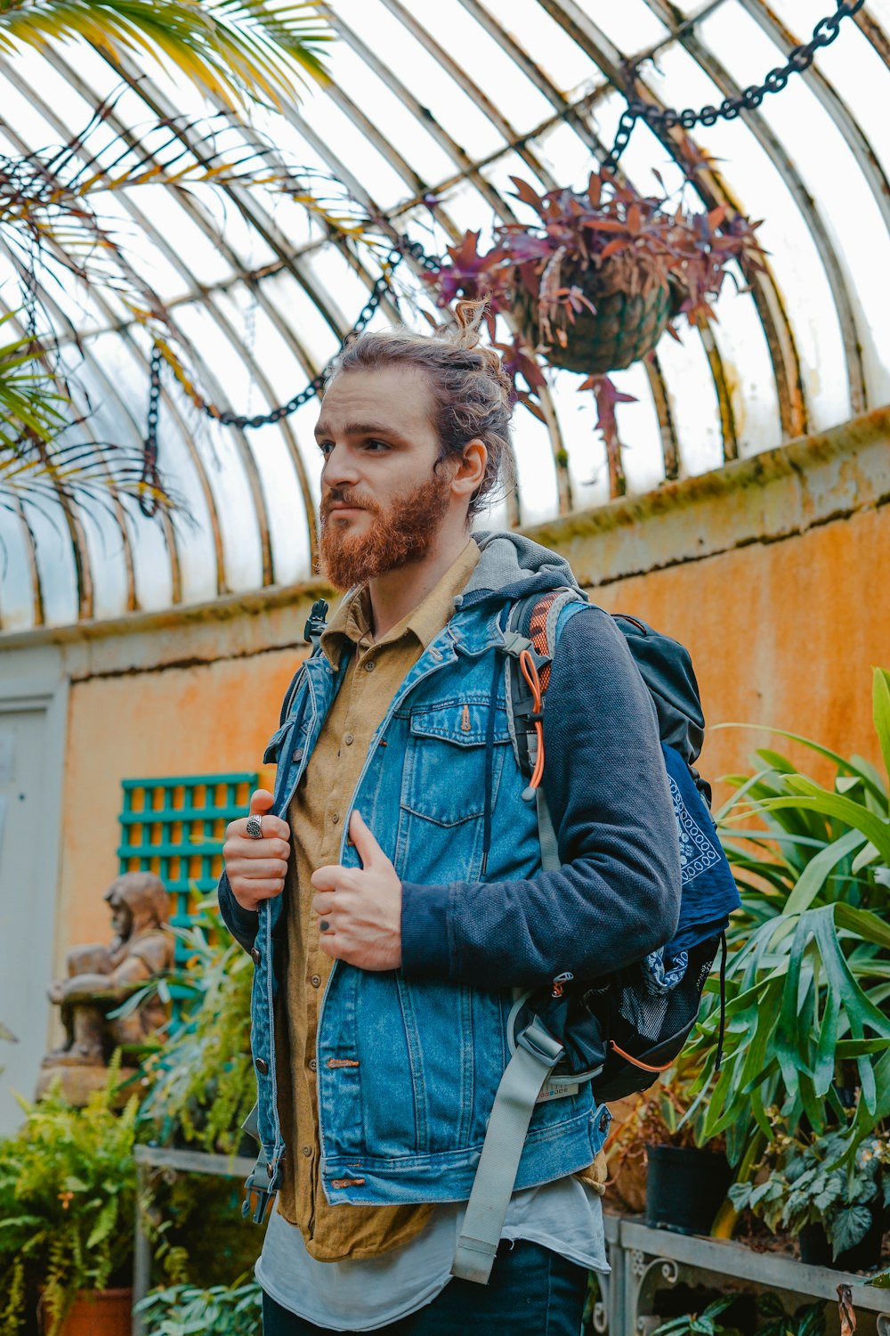 man wearing blue button-up denim jacket carrying black backpack