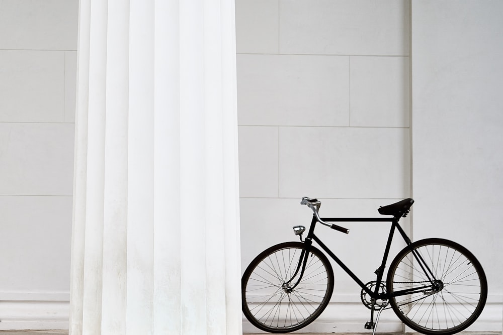 bicicleta preta em pé no edifício de concreto branco