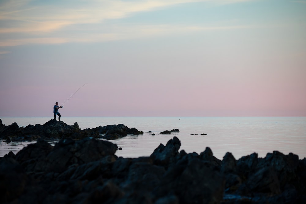 silhouette of man fishing on calm sea