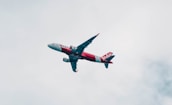 red and white airliner flying during daytime
