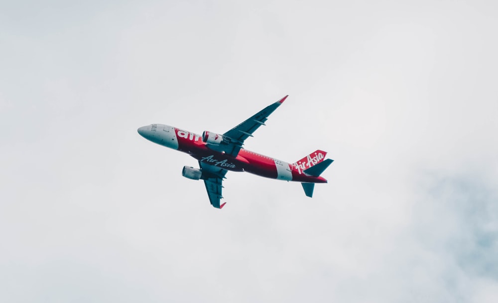 red and white airliner flying during daytime