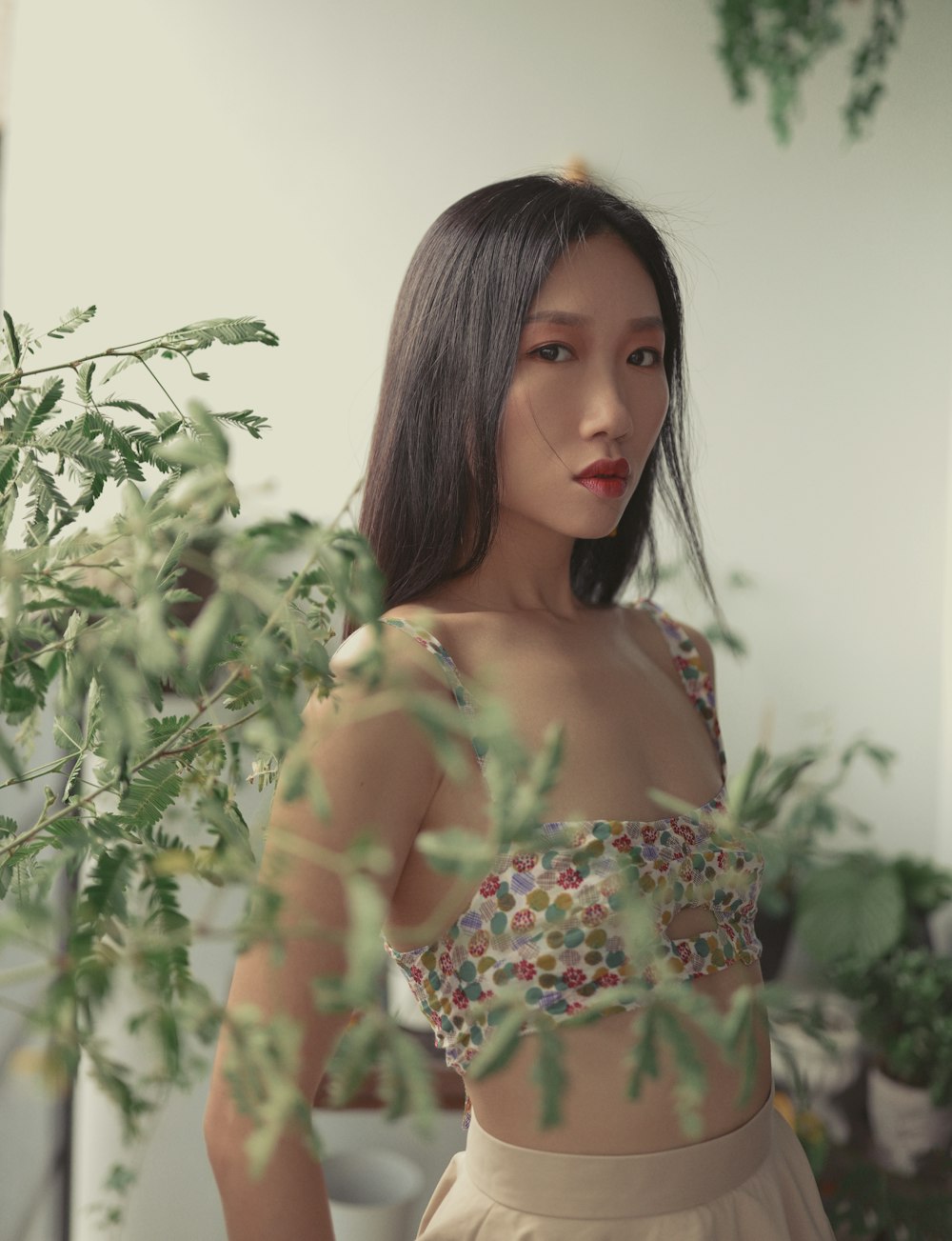 woman standing near green leaf tree wearing multicolored floral crop top