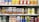A supermarket shelf displays a variety of packaged drinks, including milk tea, lemon tea, apple juice, orange juice, coffee drinks, and other flavored beverages. The packaging features vibrant colors and images of ingredients such as fruits and coffee beans. Each product is neatly arranged in rows with price tags visible.