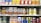 A supermarket shelf displays a variety of packaged drinks, including milk tea, lemon tea, apple juice, orange juice, coffee drinks, and other flavored beverages. The packaging features vibrant colors and images of ingredients such as fruits and coffee beans. Each product is neatly arranged in rows with price tags visible.