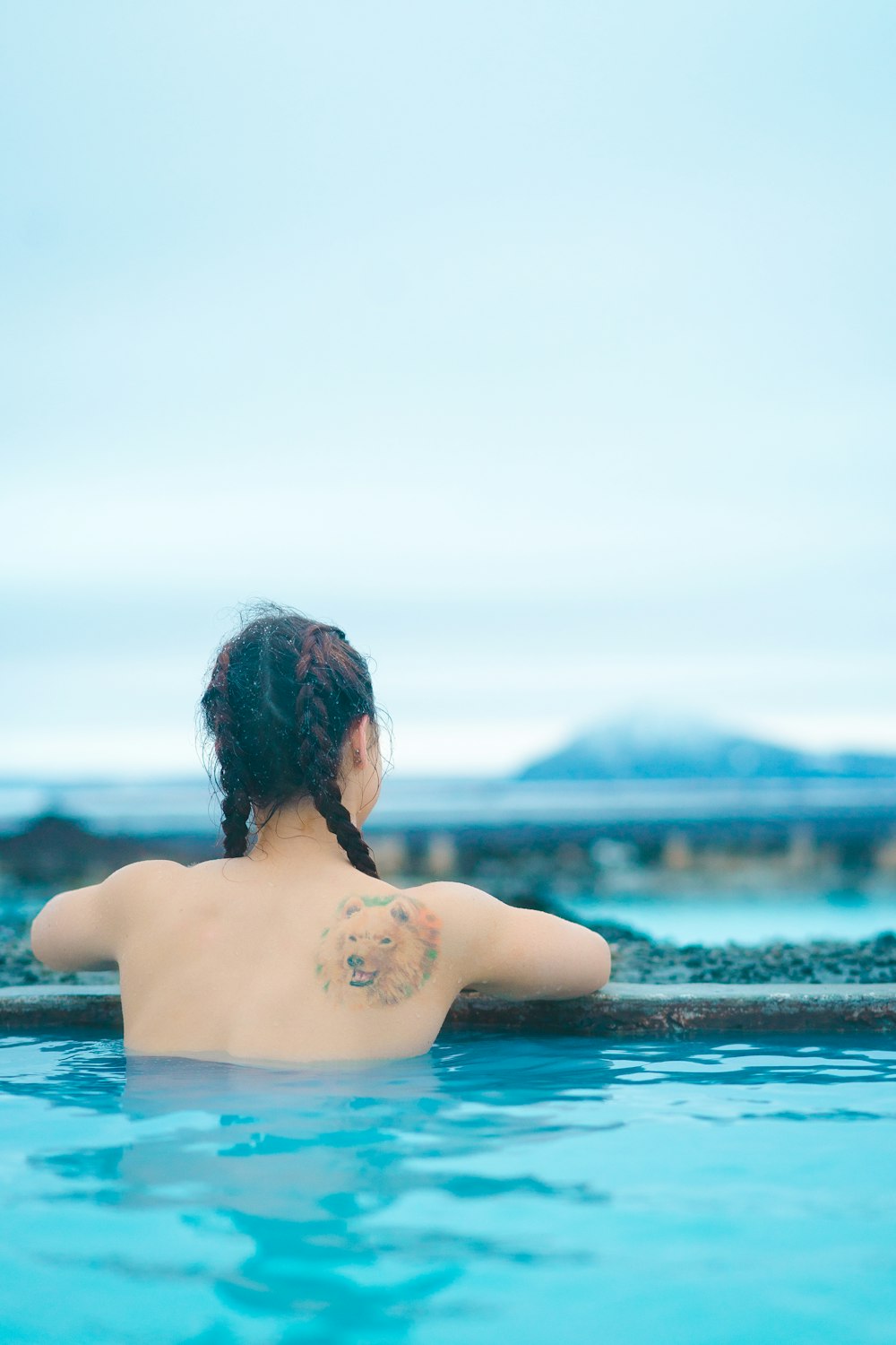 topless woman with wolf tattoo on the body of water