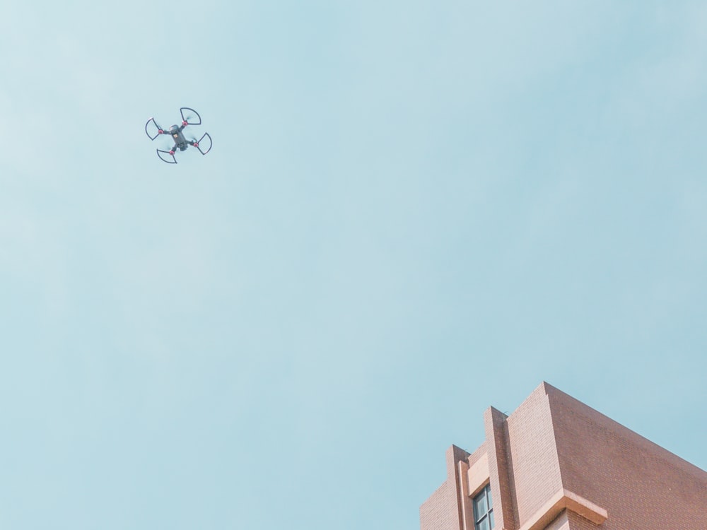 white quadcopter drone fly near brown concrete building