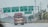 A highway scene with several green overhead road signs in both Chinese and English, indicating directions for different expressways and a bridge. A large truck is traveling on the road beneath the signs. Red lanterns hang from lampposts along the road, and trees line the highway. In the background, there are telecommunications towers.