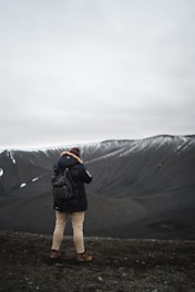 person in black parka jacket standing on brown soil