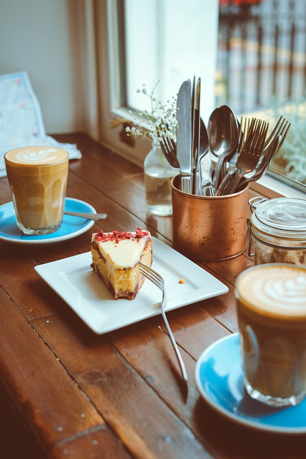 sliced cake on square ceramic plate beside of window