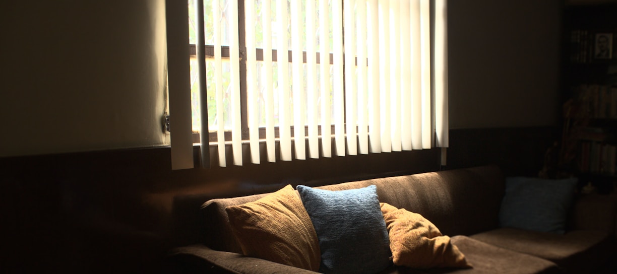brown fabric 3-seat sofa in front of white window blinds cover window