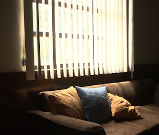 brown fabric 3-seat sofa in front of white window blinds cover window