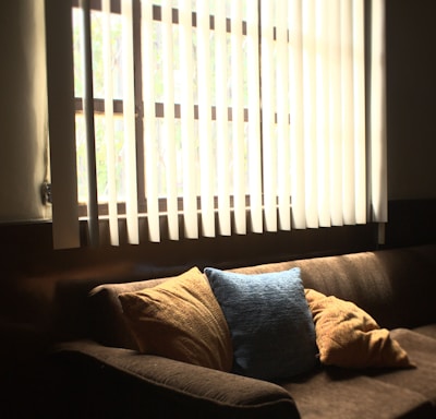 brown fabric 3-seat sofa in front of white window blinds cover window