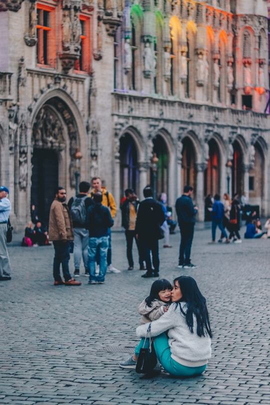 woman kissing girl while sitting near building in Grand Place Belgium