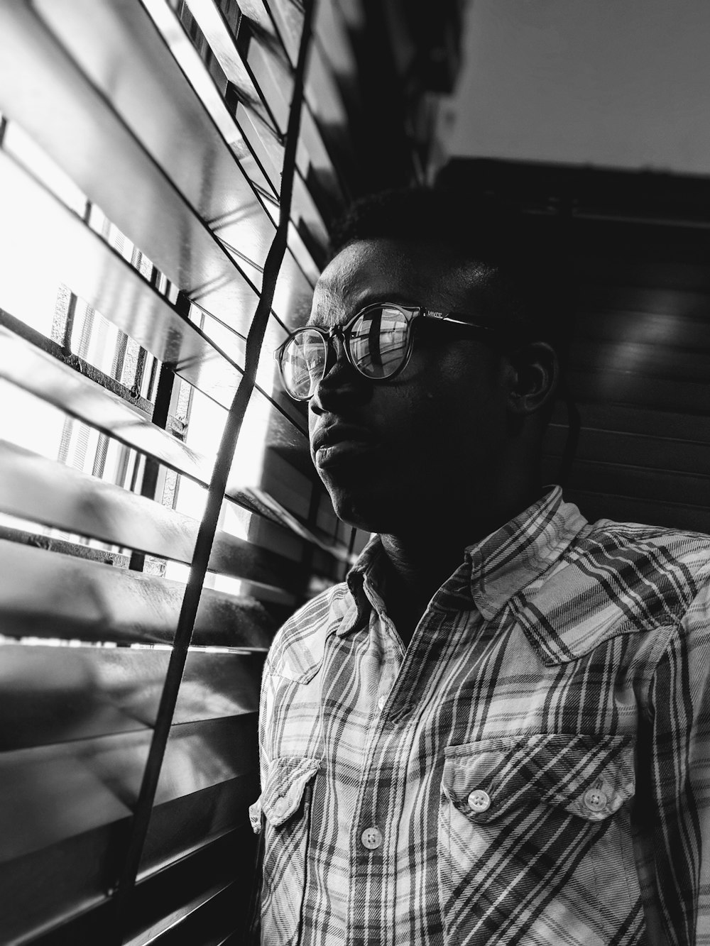 grayscale photo of man near window