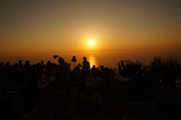 Smiling guests enjoying a sunset view from the hotel terrace with city lights.
