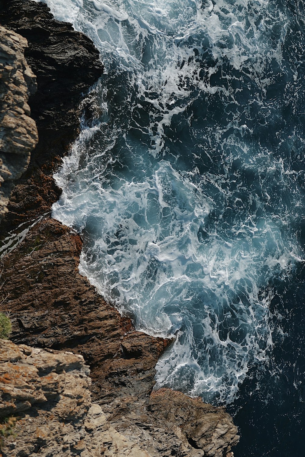 昼間の灰色の岩の崖に波しぶきを上げる