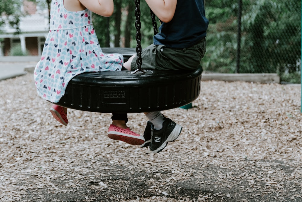 two children playing on tire swing