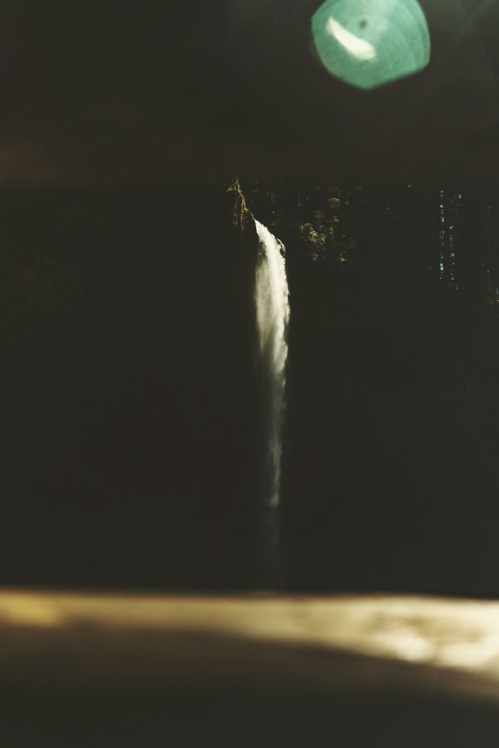 a green frisbee flying over a waterfall at night