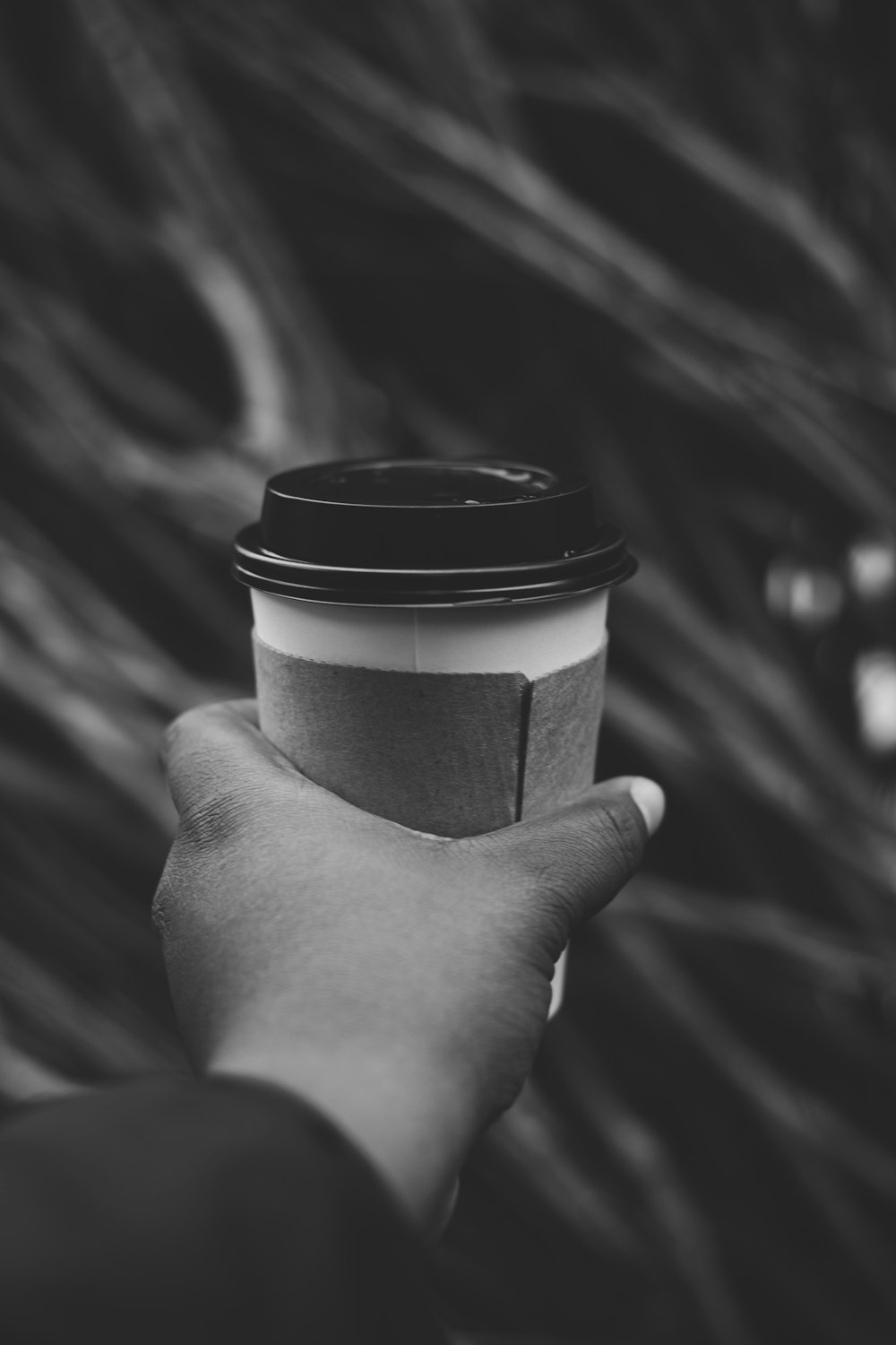 grayscale photo of person holding disposable cup