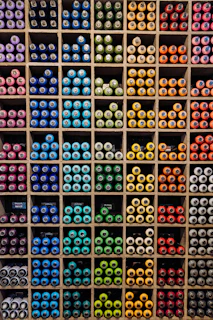 A vibrant display of colorful paint cans arranged neatly on wooden shelves.