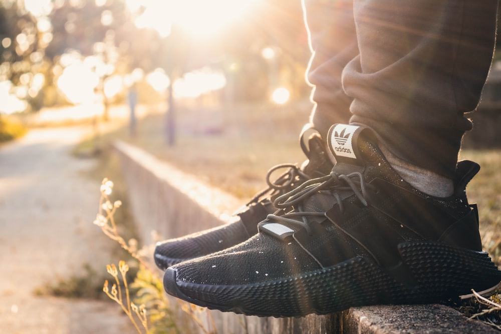 Foto persona con un par de zapatillas adidas negras – Imagen Zapato gratis  en Unsplash
