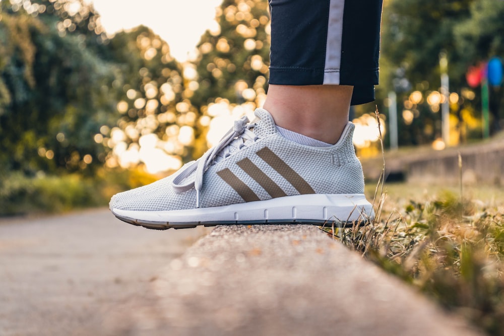 selective focus photography of unpaired blue and white adidas running shoe  leaning on concrete pavement at daytime photo – Free Sneaker Image on  Unsplash