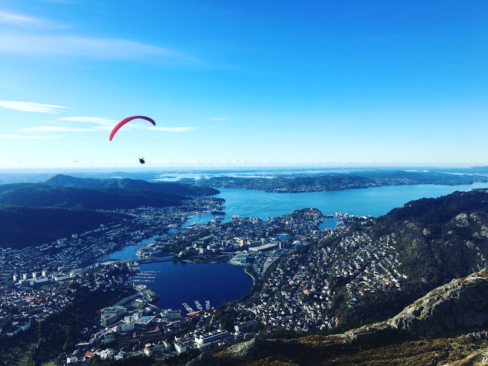 paraglider above buildings and body of water at daytime