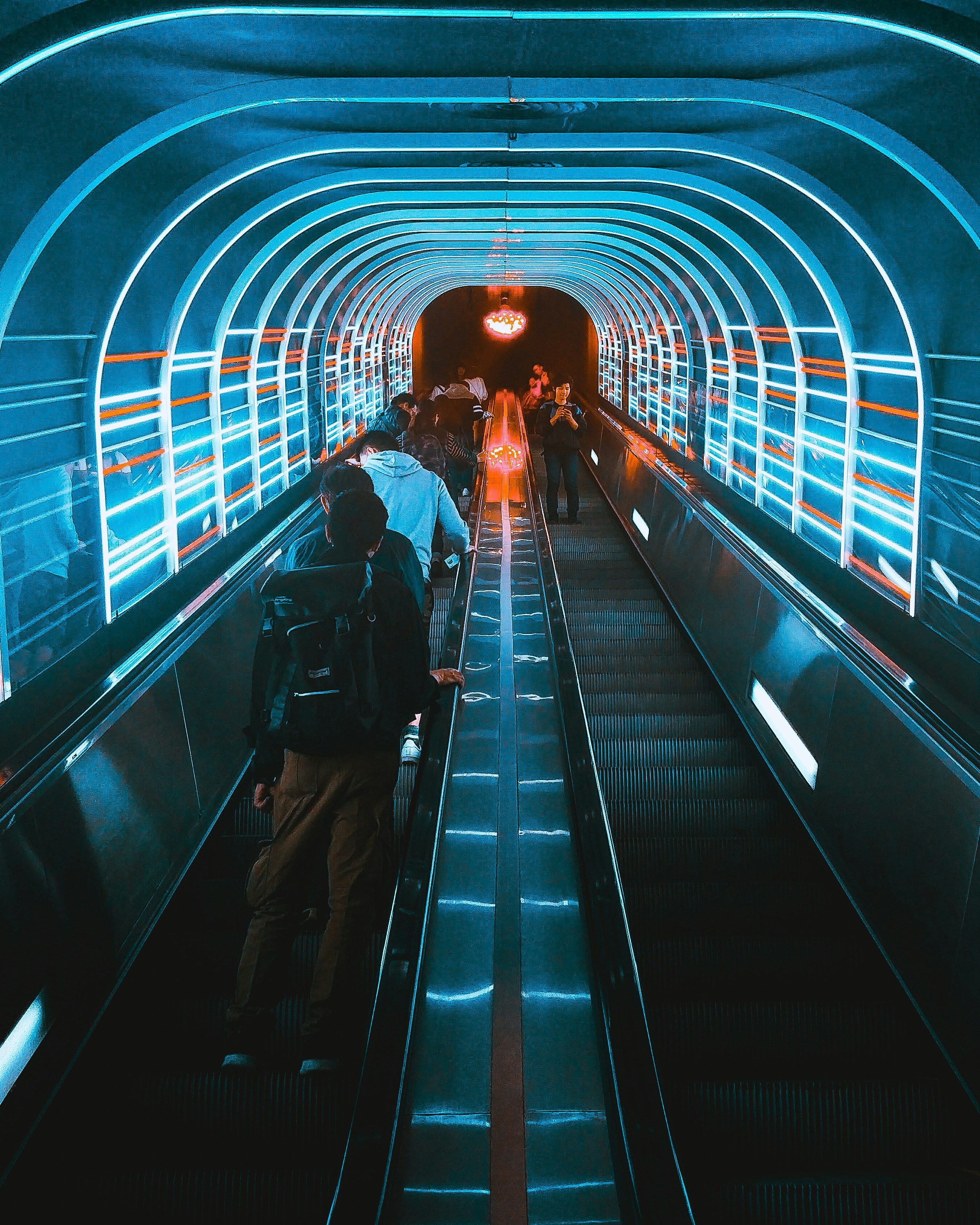 photo of people using escalators under blue LED lights