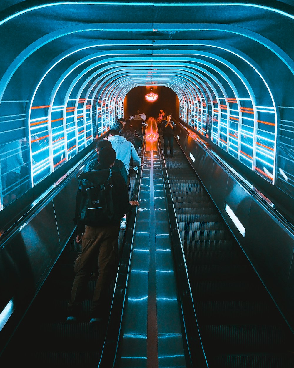 photo of people using escalators under blue LED lights