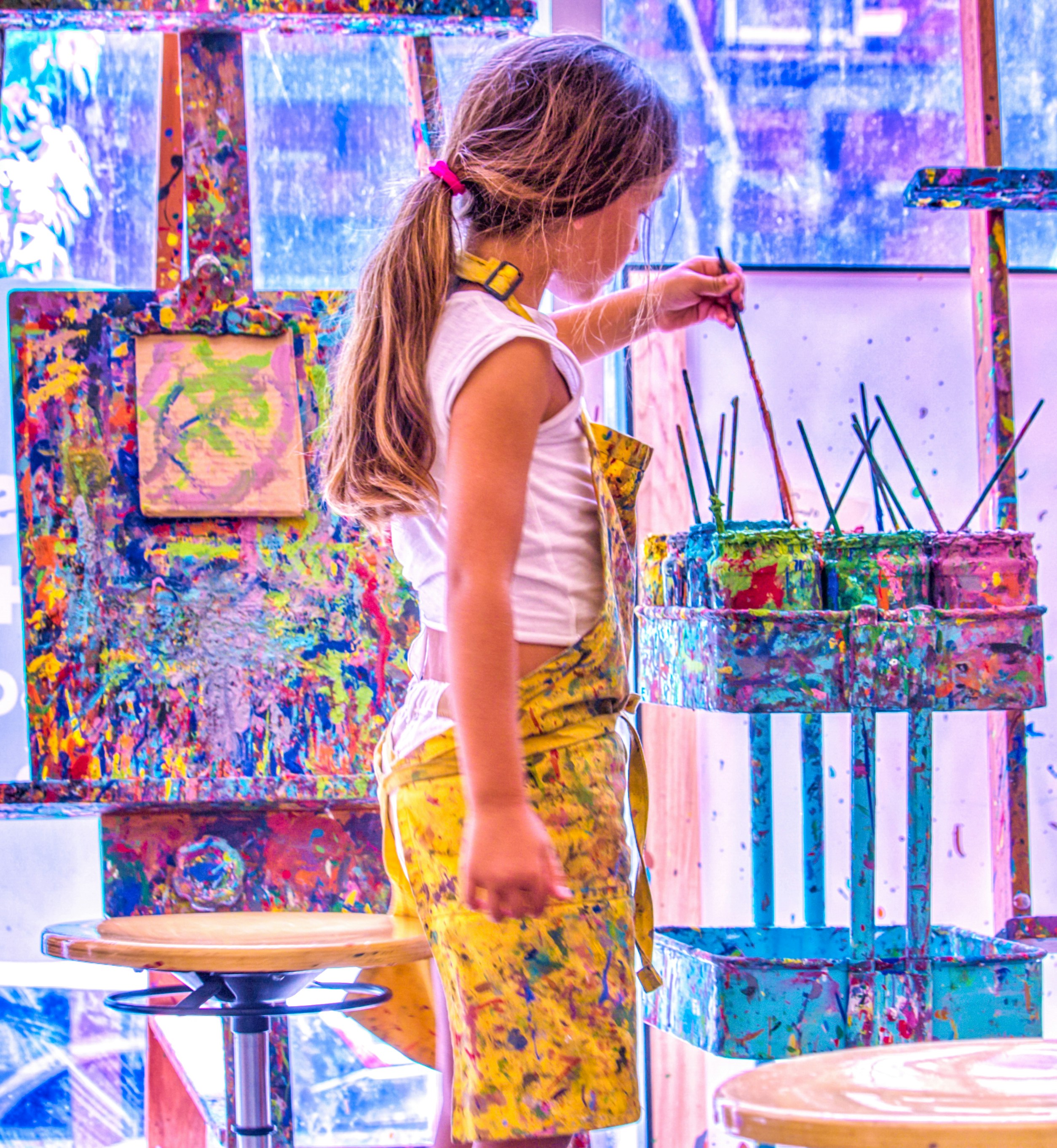 Young girl painting at a table, colorful artwork, creative expression, warm indoor light