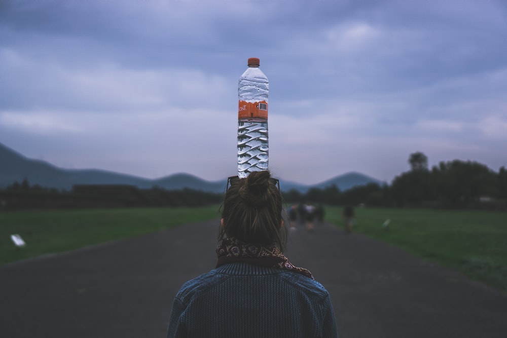 mulher colocando uma garrafa de plástico transparente em sua cabeça