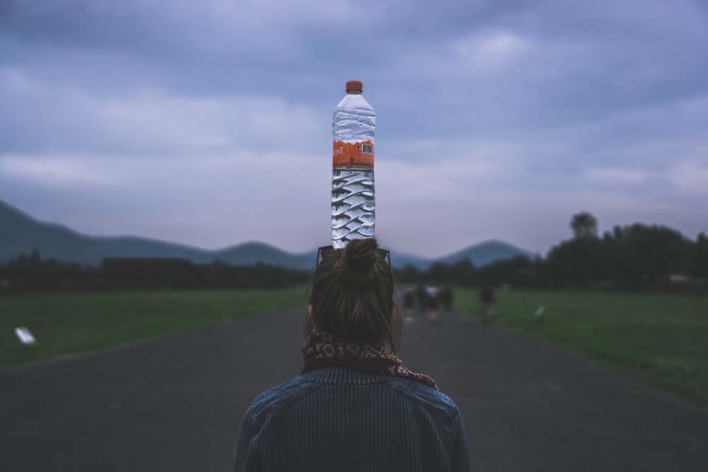 Frau setzt sich eine durchsichtige Plastikflasche auf den Kopf