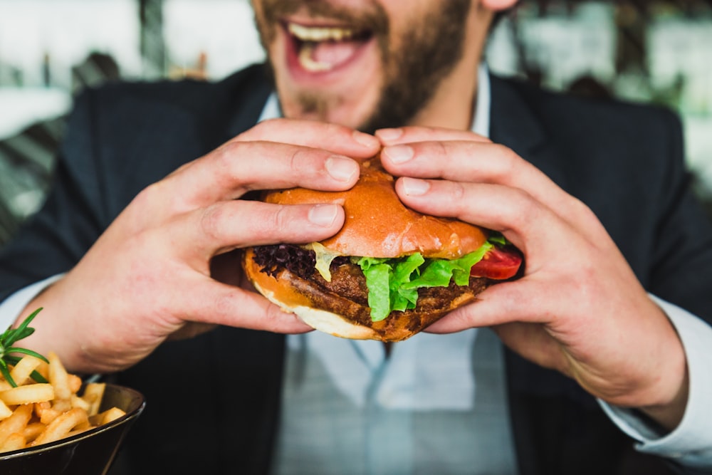 Person mit Burgerbrötchen mit Gemüse und Fleisch