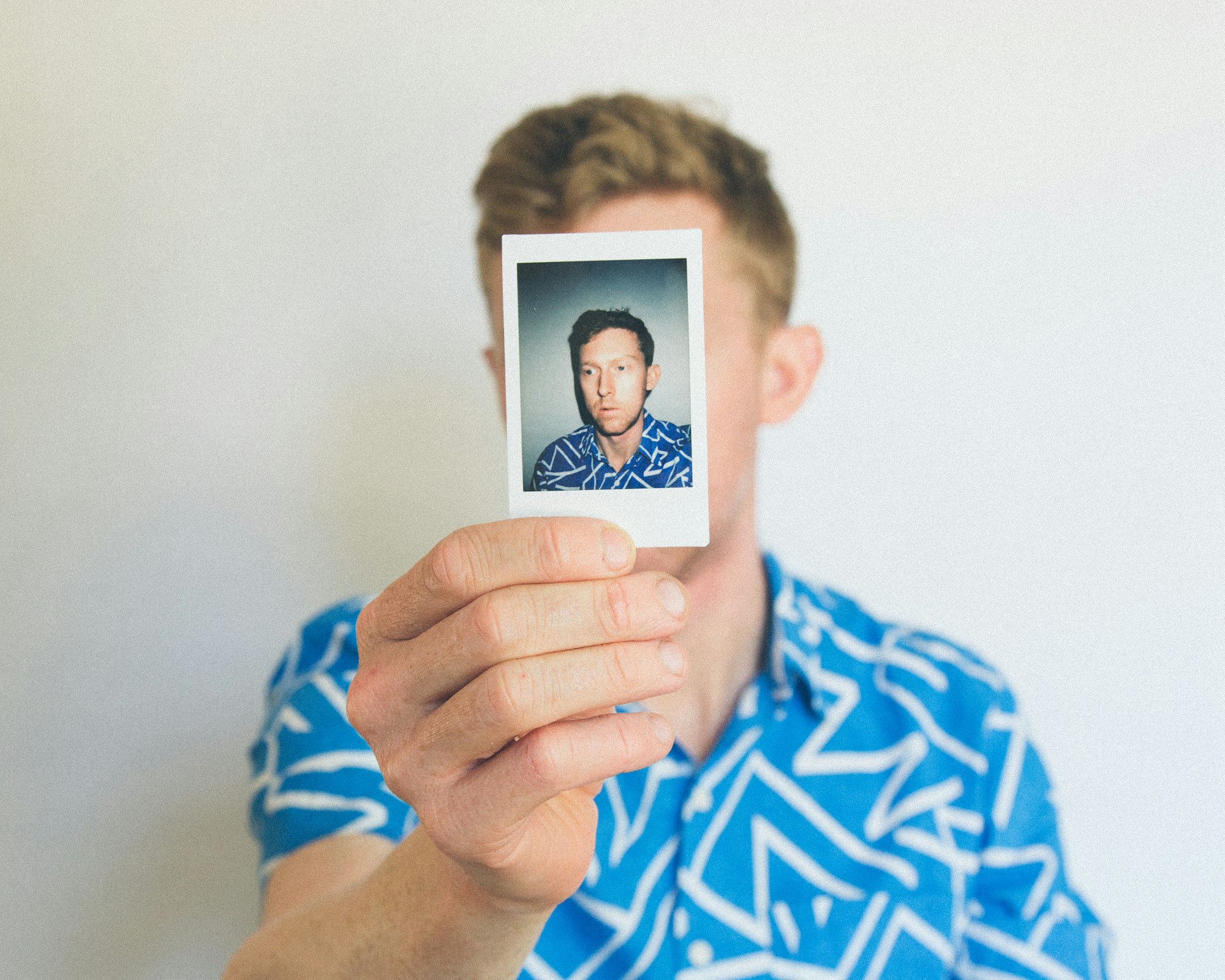 Image of a man holding a picture in front of his
face
